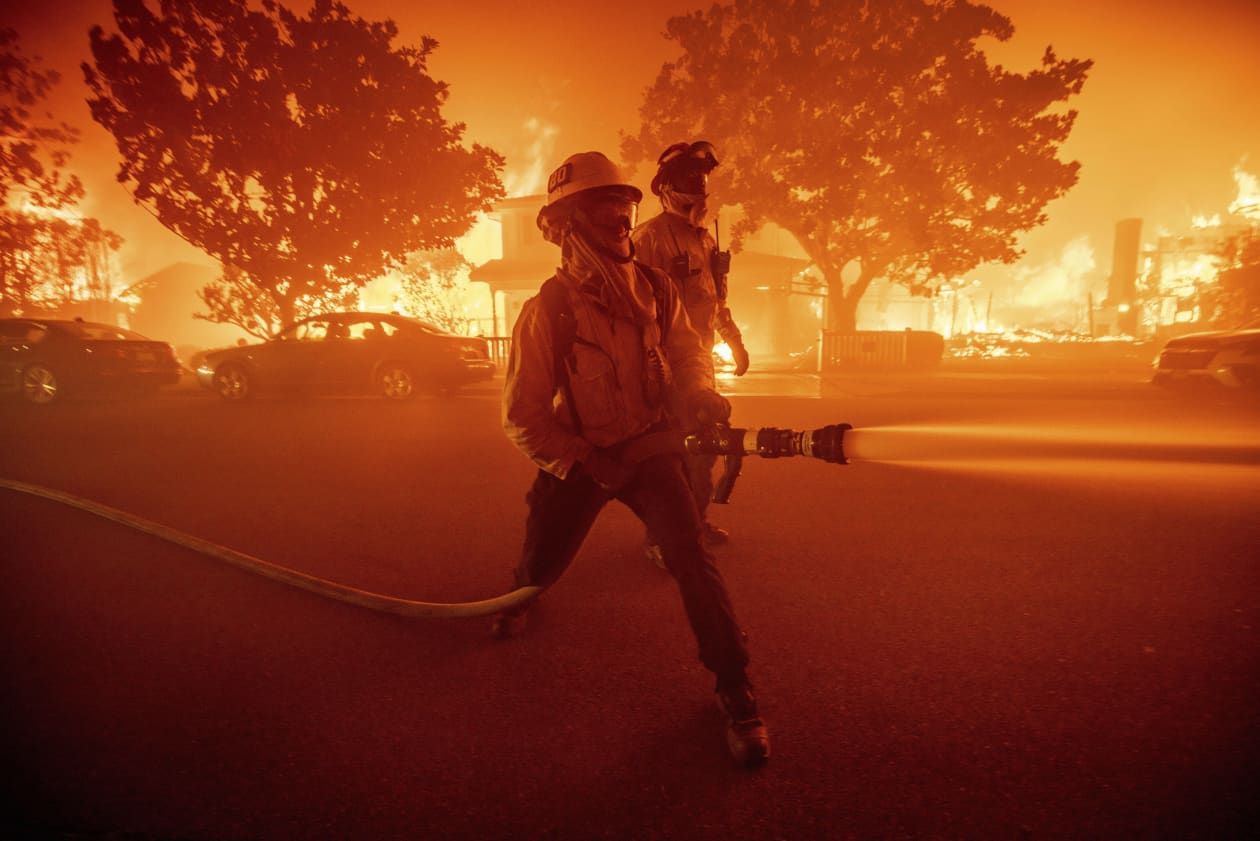 Firefighters battle the Palisades Fire as it burns neighborhood structures.